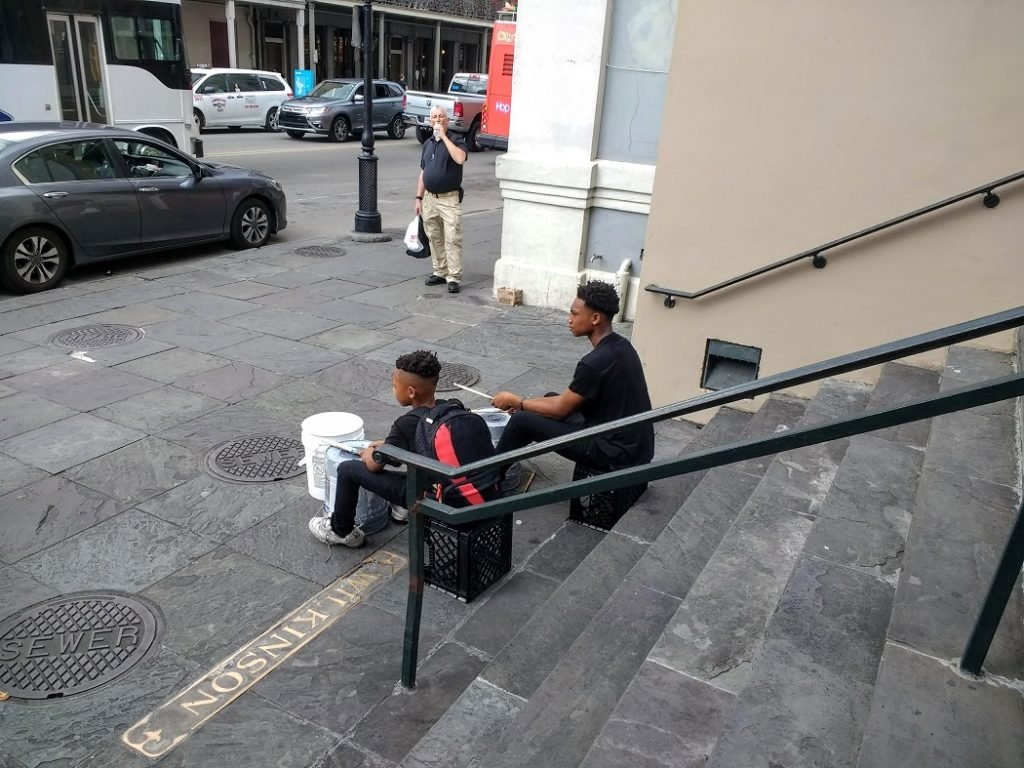 two boys drumming on plastic buckets